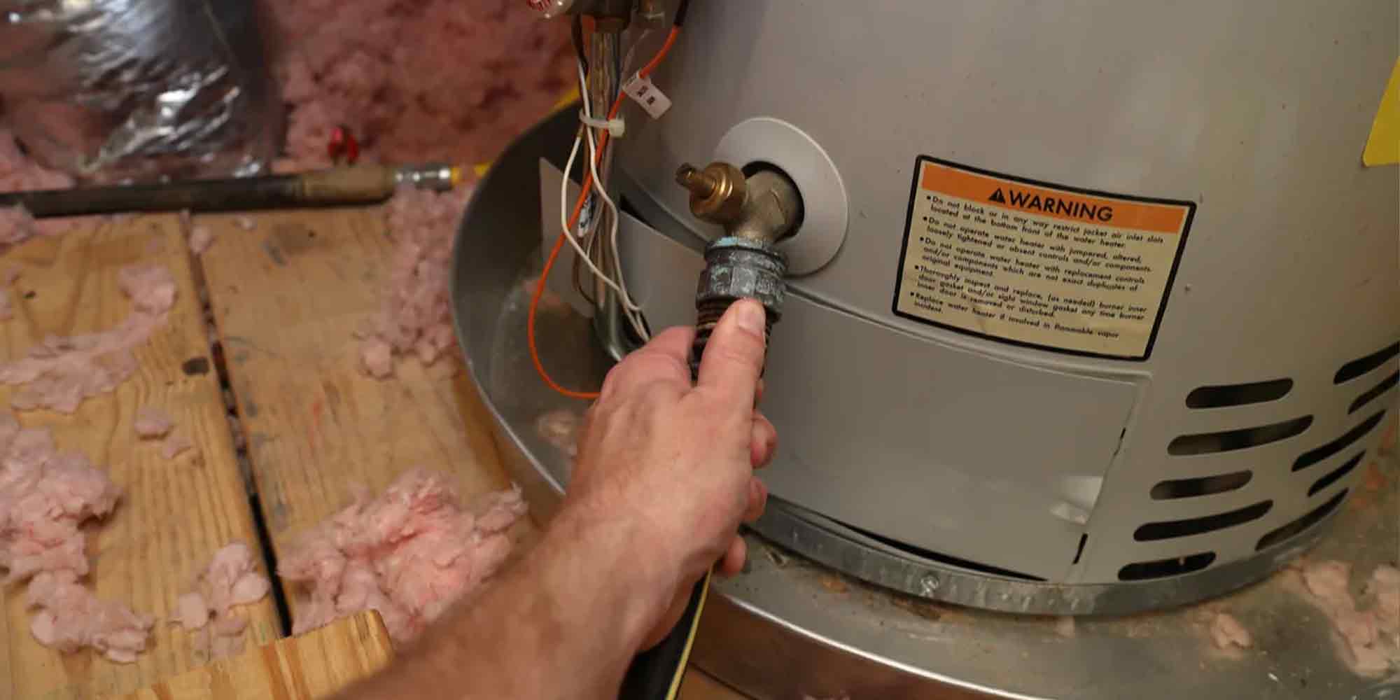 Person Holding Hose Connected to Water Heater | Monkey Wrench Plumbing, Sewer & Drain | Tankless Water Heater Repair in Utah