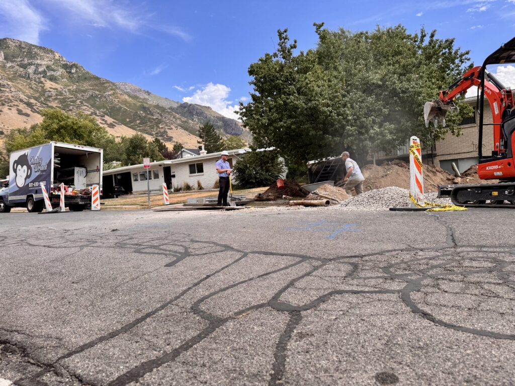 Monkey Wrench Plumbing truck parked at a Provo sewer line replacement with the mountains behind