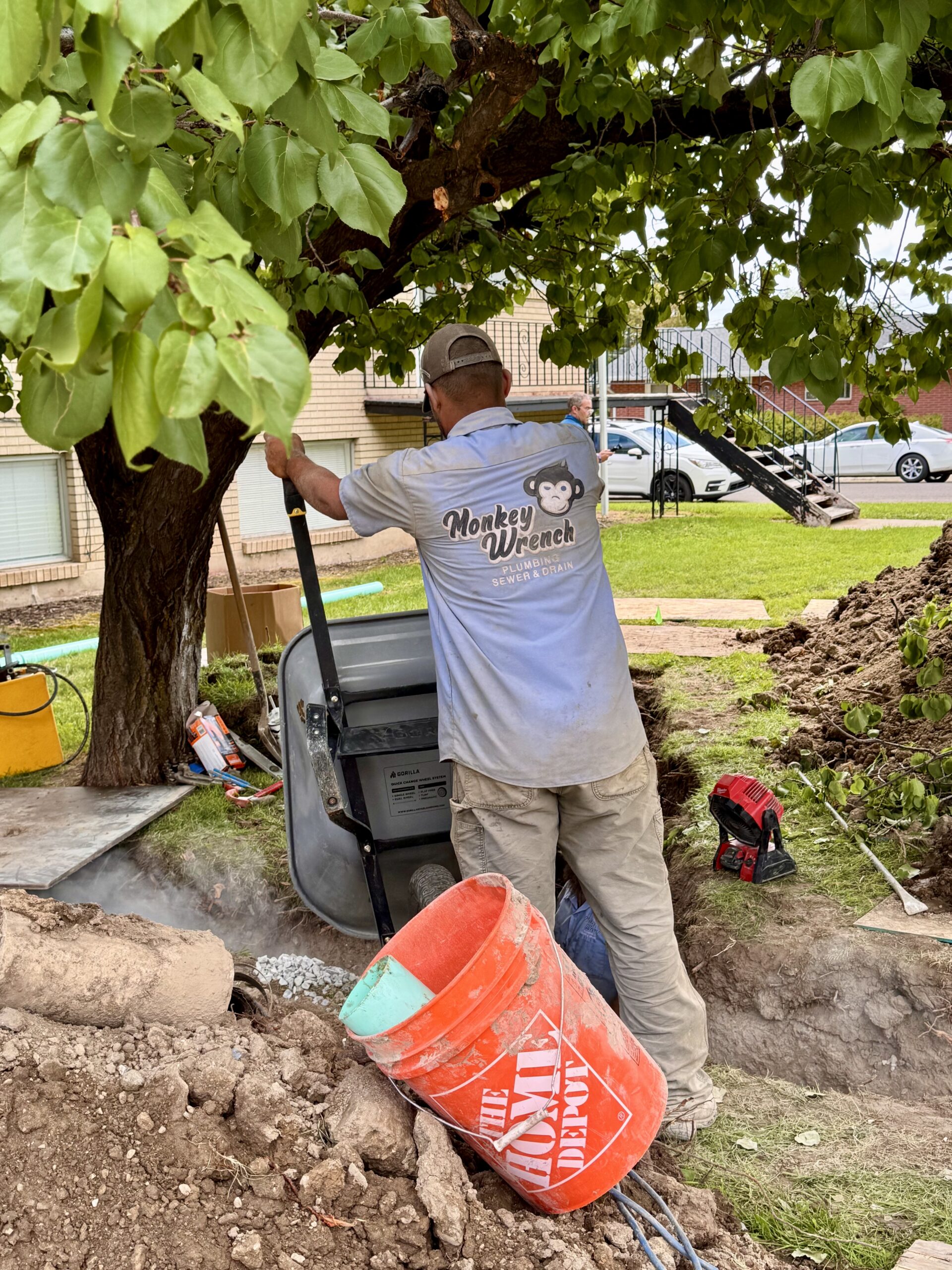 Monkey Wrench plumber backfilling a sewer trench beneath a mature tree in Provo