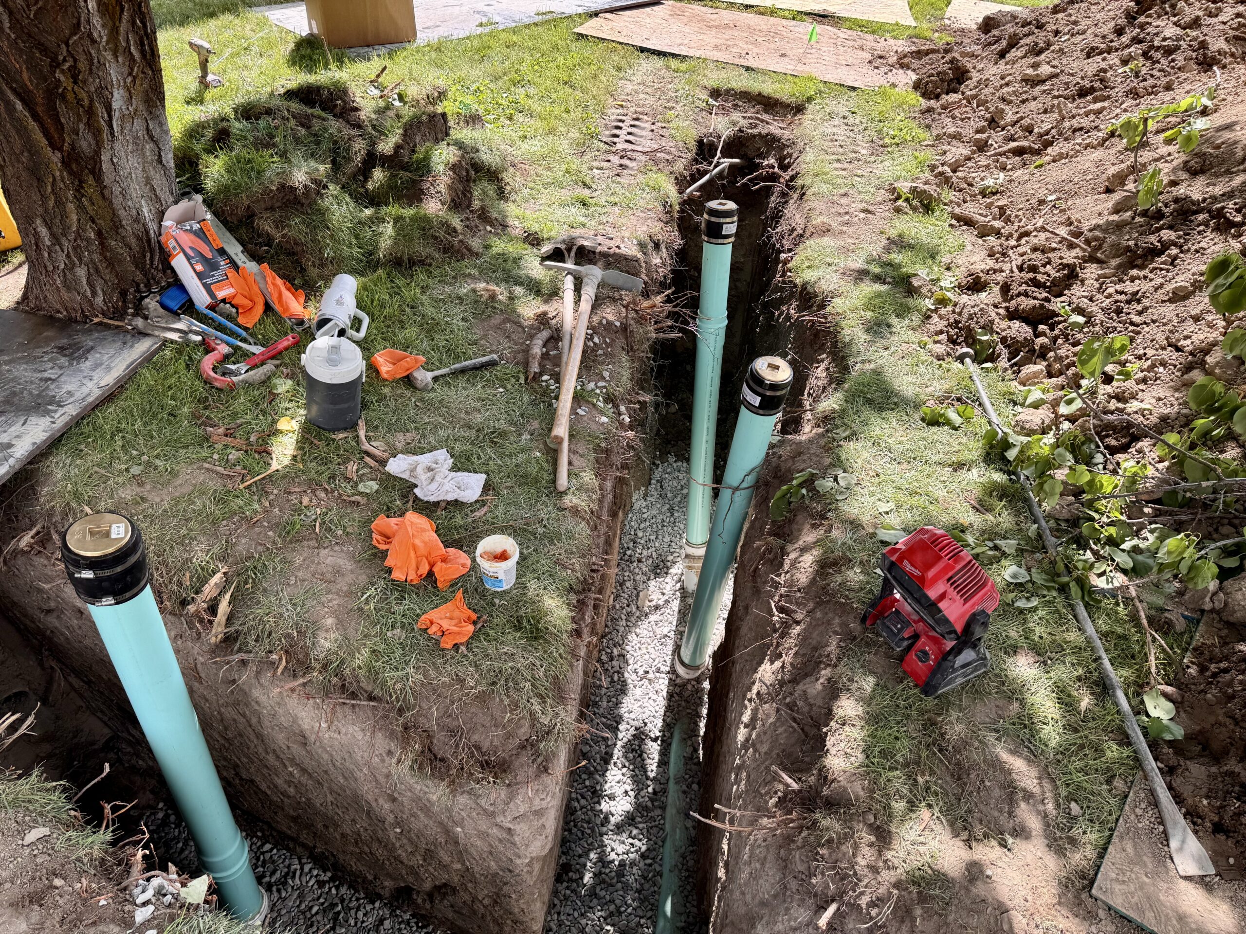 New green PVC sewer line on gravel bedding with two cleanout risers in a Provo yard